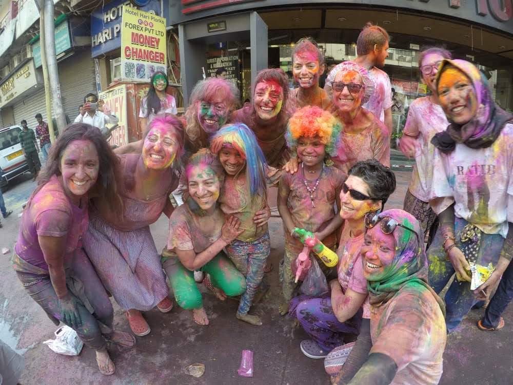 Viajeros sonriendo cubiertos de colores durante Holi